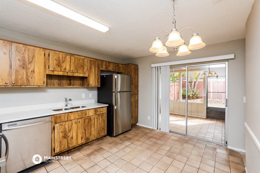 a kitchen with a sliding glass door to the patio and a stainless steel refrigerator