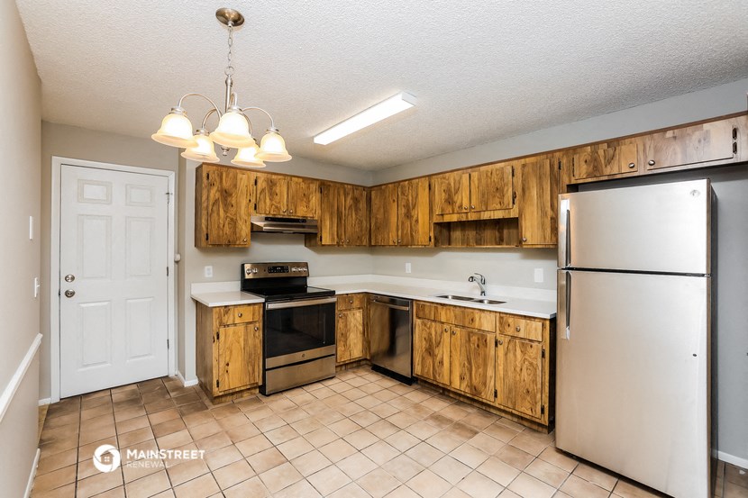 a kitchen with wooden cabinets and a refrigerator and a sink
