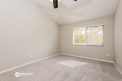 the spacious living room with carpet and a window