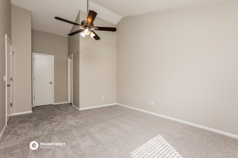 the spacious living room with ceiling fan and carpet