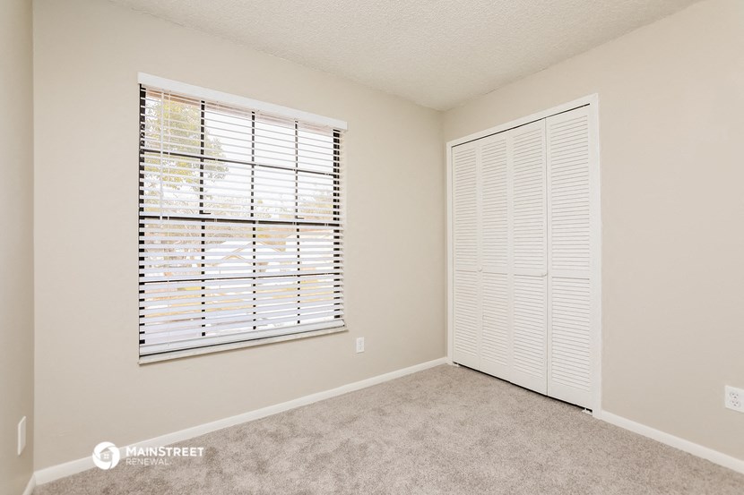 a bedroom with a large window and a door to a closet