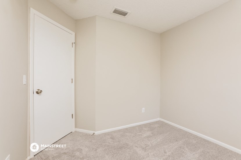 a bedroom with a door and carpeted floor