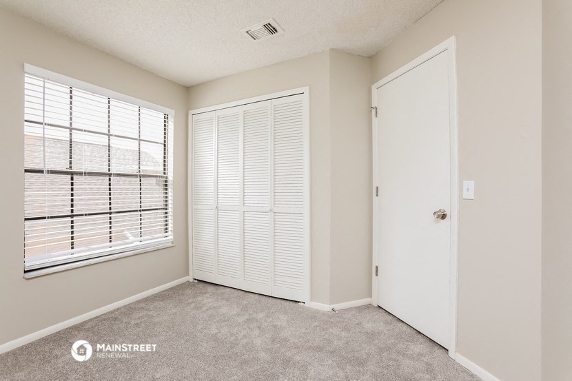a bedroom with a door and a window and a closet