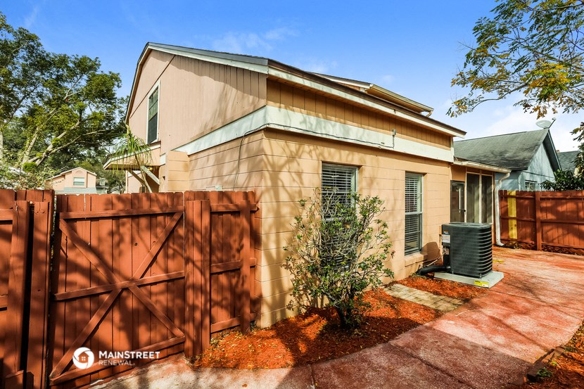 a house with a wooden fence and a driveway next to it