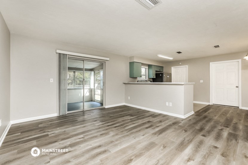 a living room with a kitchen and a sliding glass door