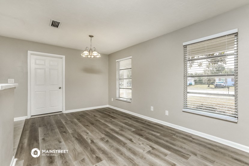 an empty living room with a white door and a window