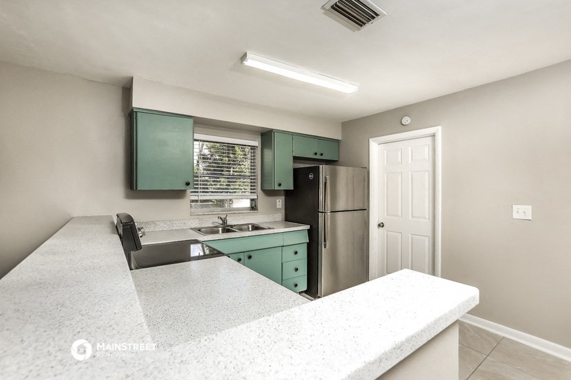 a kitchen with green cabinets and a stainless steel refrigerator