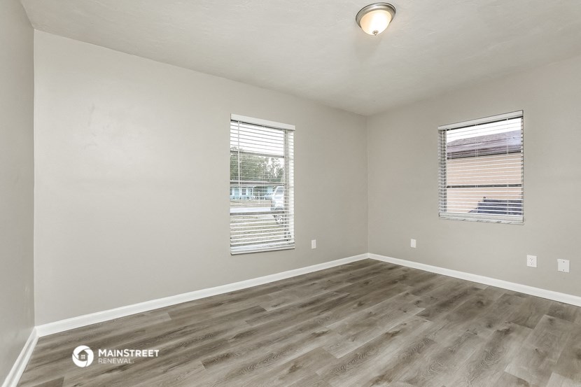 the spacious living room with wood flooring and two windows