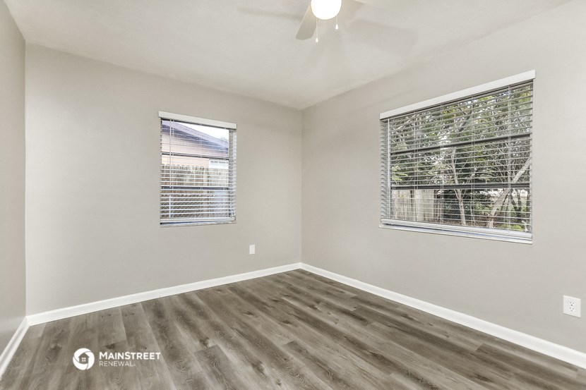 the spacious living room with two windows and wood flooring
