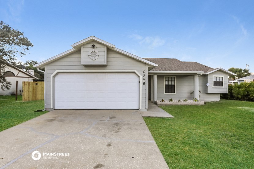 a white house with a white garage door and a lawn