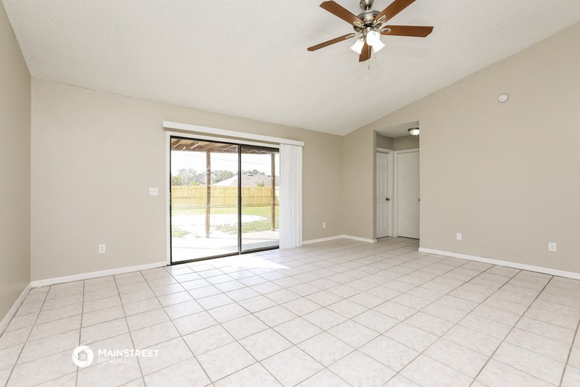 an empty living room with a ceiling fan and a sliding glass door