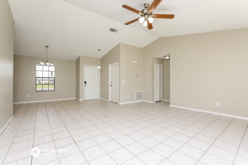 the spacious living room with tile flooring and a ceiling fan