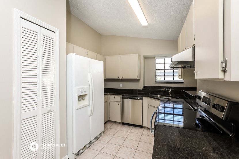 an empty kitchen with black counter tops and white appliances