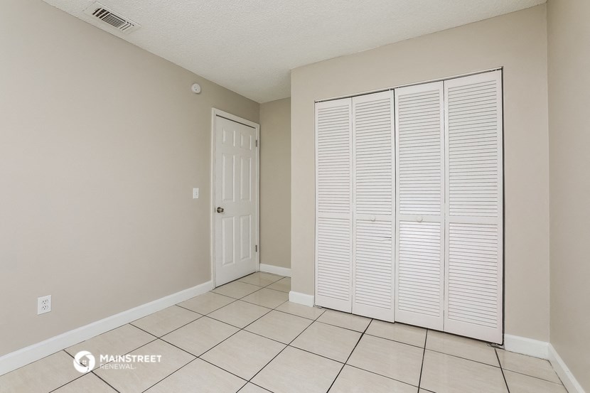 the living room of an apartment with two closets and a tiled floor