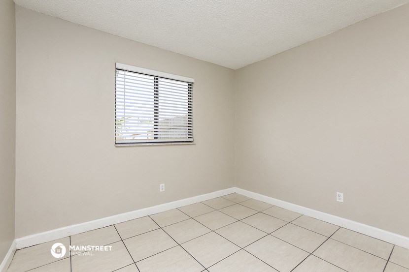 an empty room with a window and a tiled floor