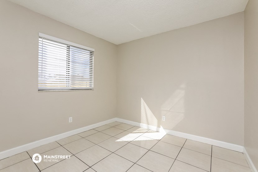an empty living room with a window and a tiled floor