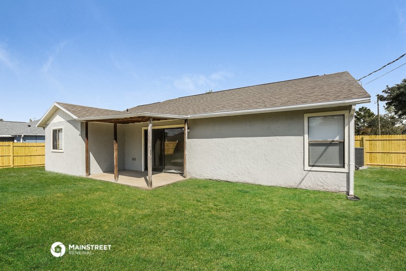 a small white house with an open door in a yard