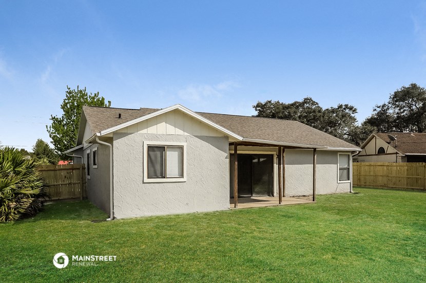 a small white house with an open door in a backyard