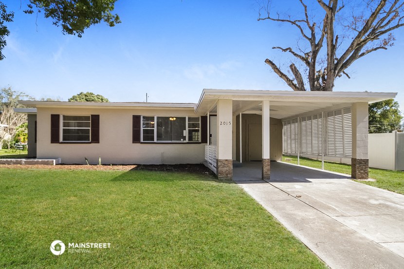 a white house with a lawn and a tree