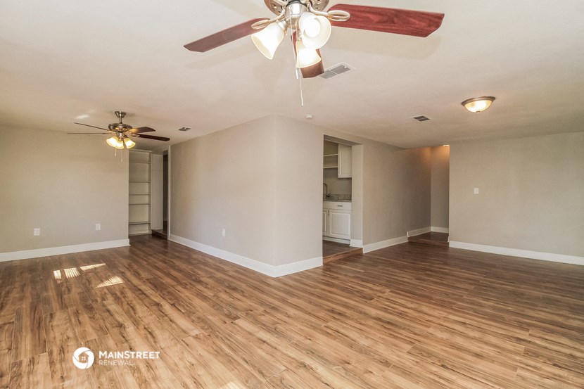 the living room and kitchen of an empty house with a ceiling fan