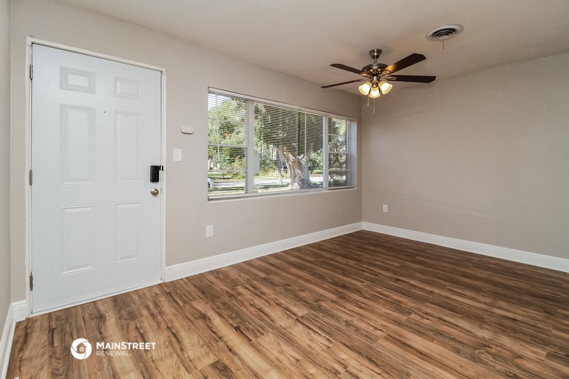 an empty living room with a window and a ceiling fan