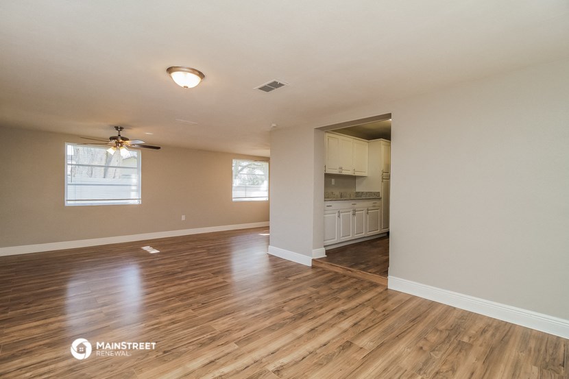 an empty living room and kitchen with wood flooring