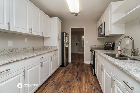 a large kitchen with white cabinets and marble counter tops