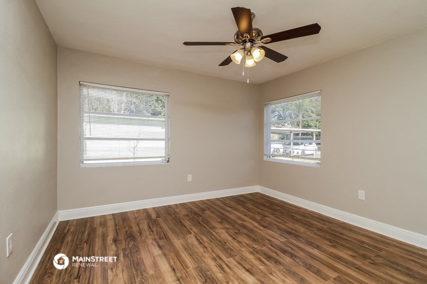 an empty living room with a ceiling fan and a window