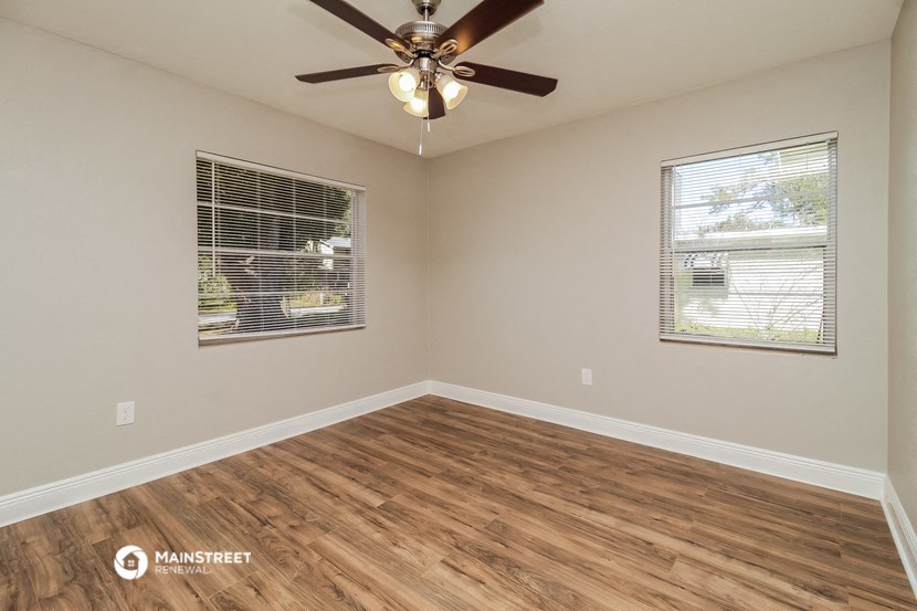 an empty living room with a ceiling fan and a window