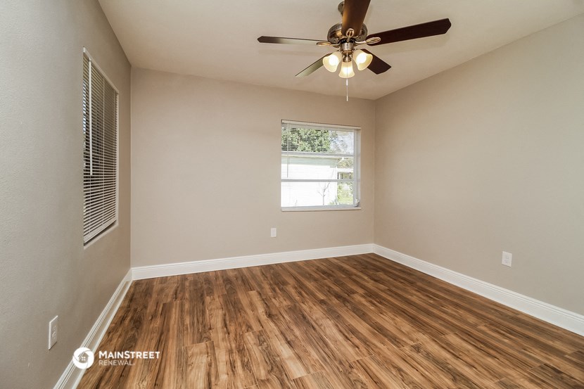 an empty living room with a ceiling fan and a window