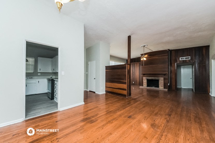 an empty living room with wood floors and a fireplace
