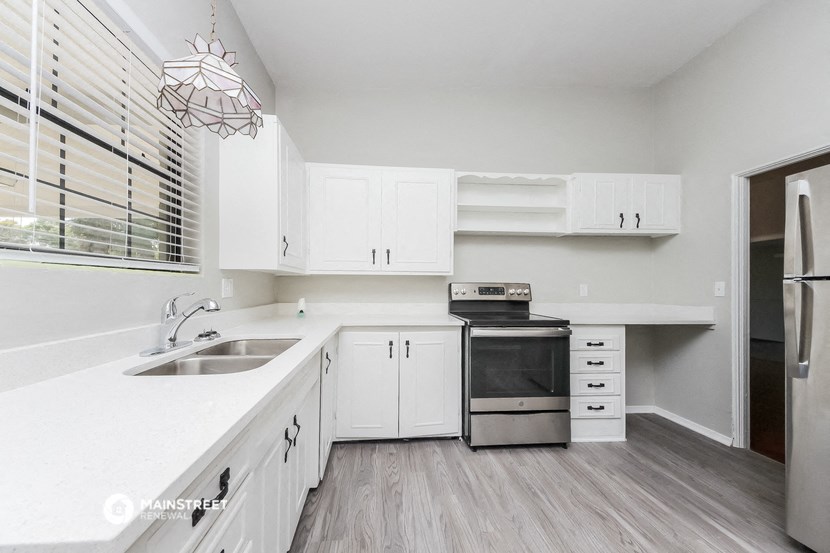 a white kitchen with white cabinets and a window