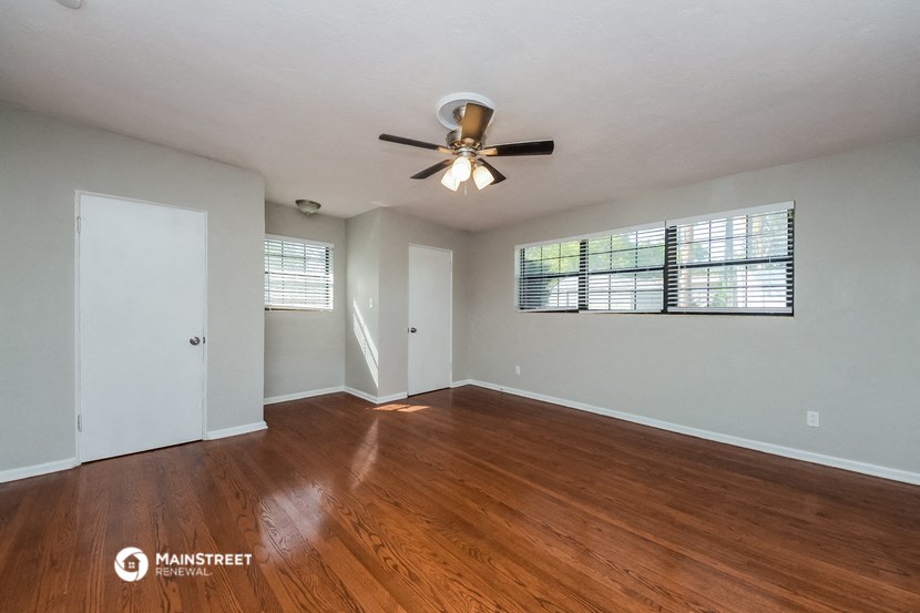 an empty living room with wood floors and a ceiling fan