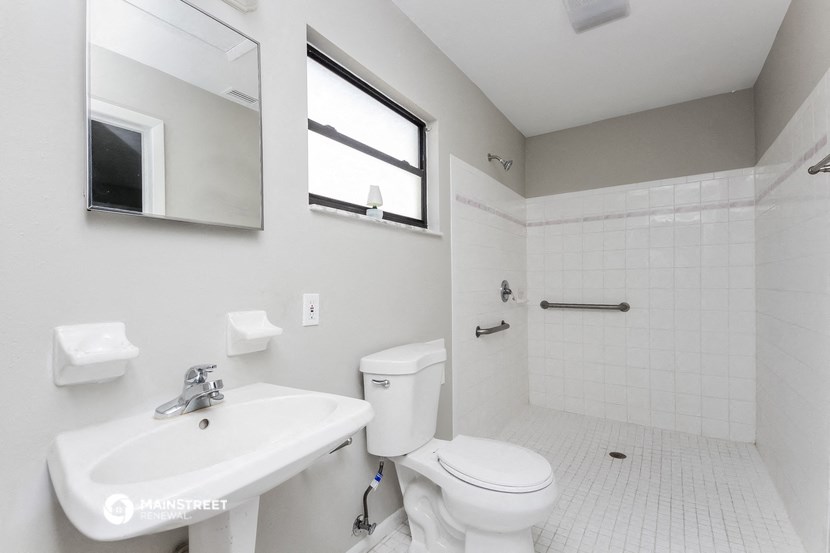 a white bathroom with a sink toilet and a window