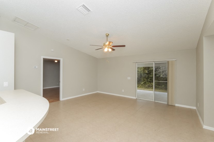 an empty living room with a ceiling fan and a window