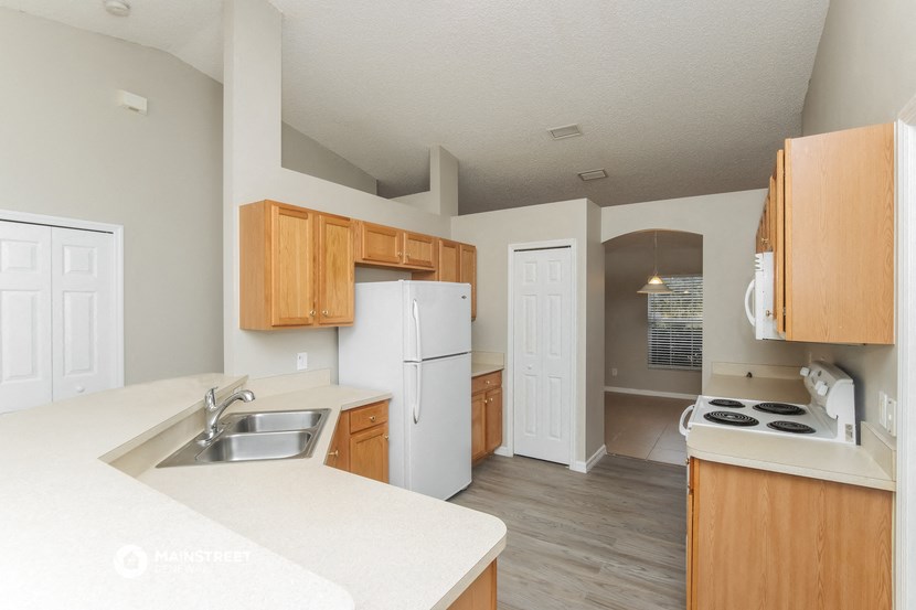 an empty kitchen with white appliances and wooden cabinets