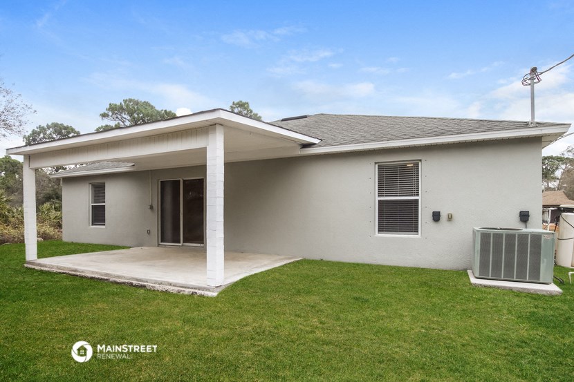 a small white house with a lawn and a driveway