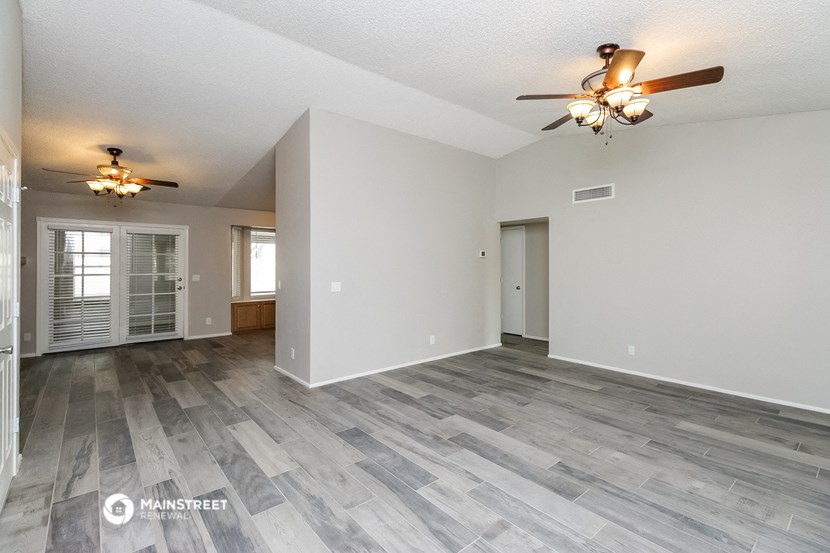the living room and dining room of an empty house with a ceiling fan