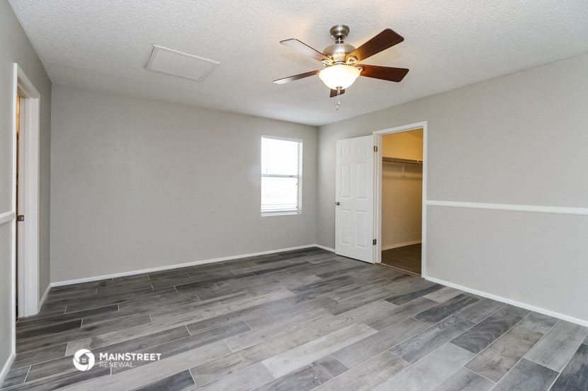 the spacious living room with wood flooring and a ceiling fan