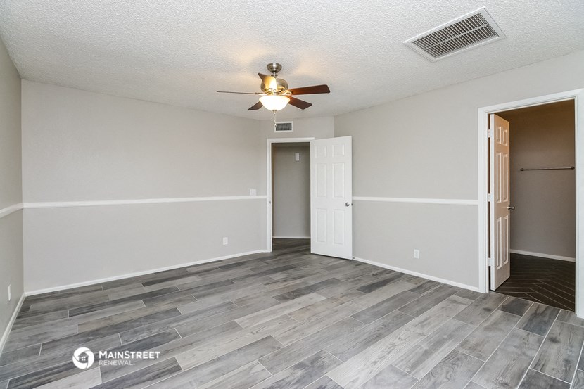an empty living room with a ceiling fan and a door to a closet
