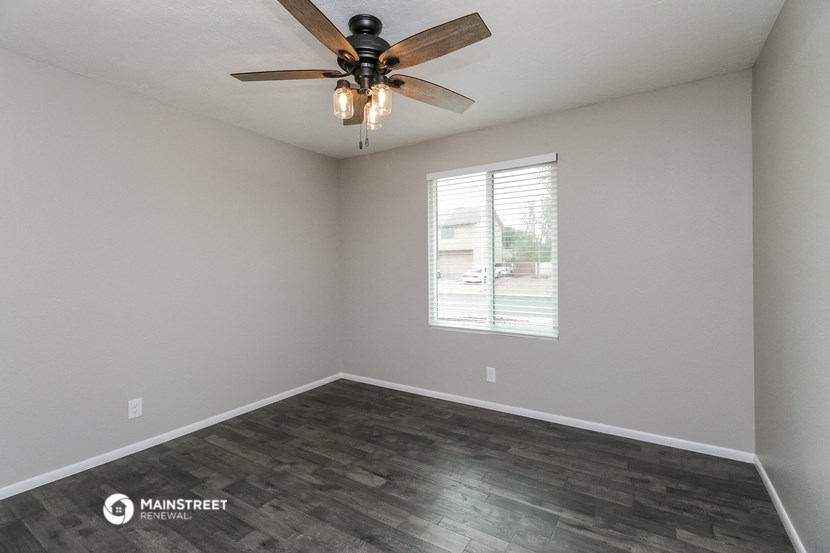 the spacious living room with a ceiling fan and a window