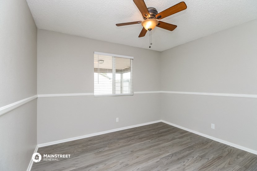 the spacious living room with a ceiling fan and a window