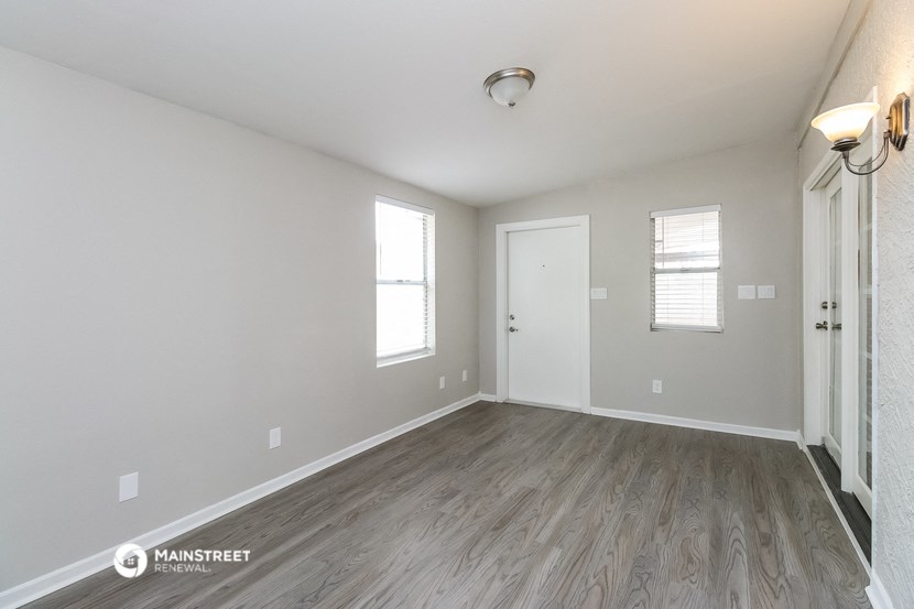 the spacious living room with wood flooring and white walls