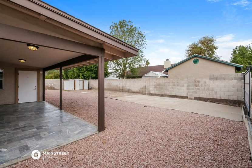 a patio with a wall and a driveway next to a house