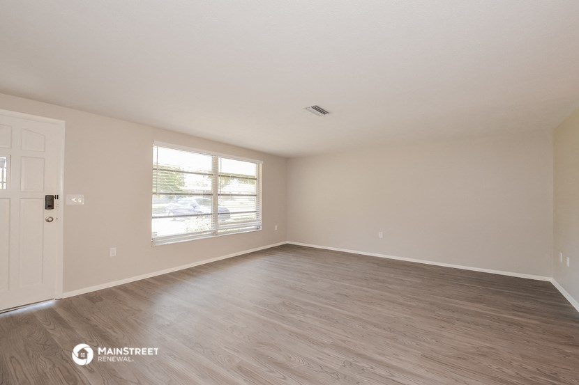 the spacious living room with wood flooring and a large window