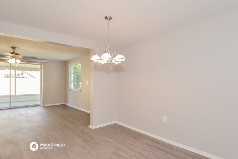 the living room and dining room of a house with white walls and wood floors