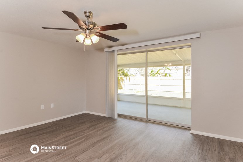 an empty living room with a ceiling fan and a window