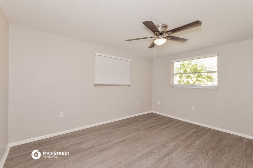 the spacious living room with ceiling fan and wood flooring