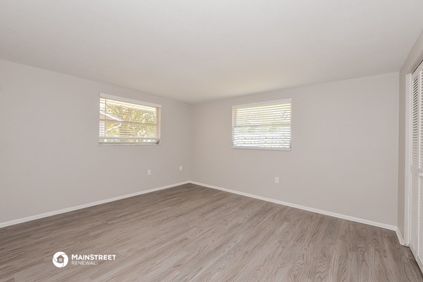 the spacious living room with wood flooring and two windows