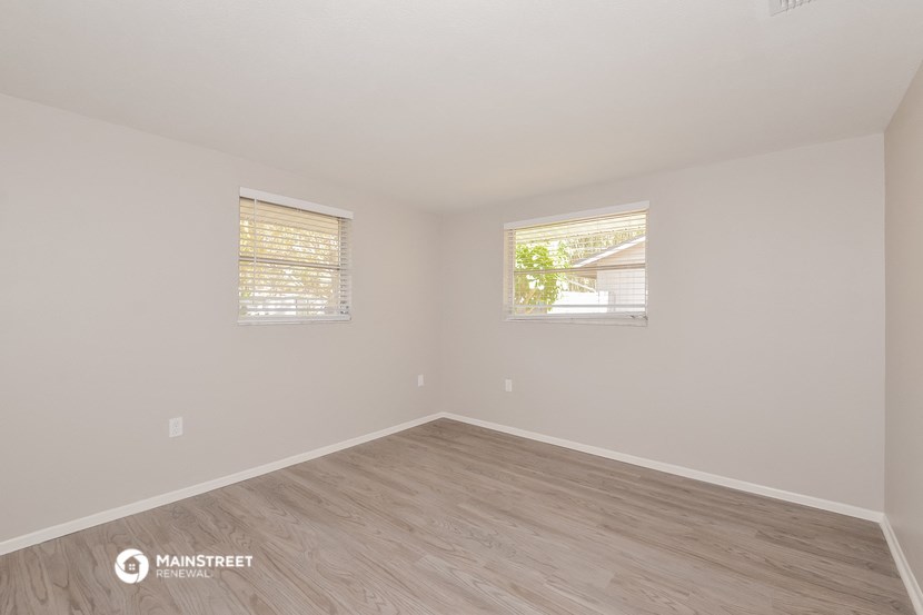 the spacious living room with wood flooring and two windows